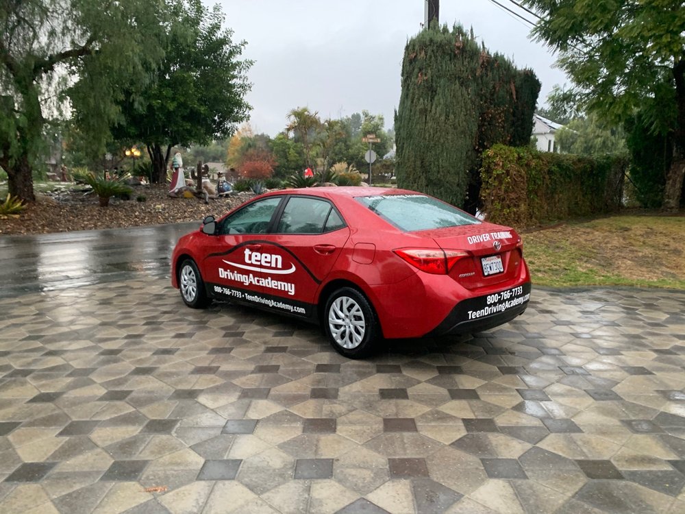 Teen Driving Academy's red training Corolla parked in a residential driveway in Brea, California.